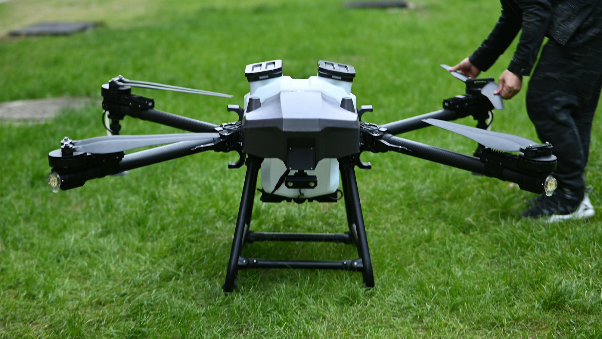 a-man-standing-next-to-a-black-and-white-flying-device.jpg A man standing next to a black and white flying device